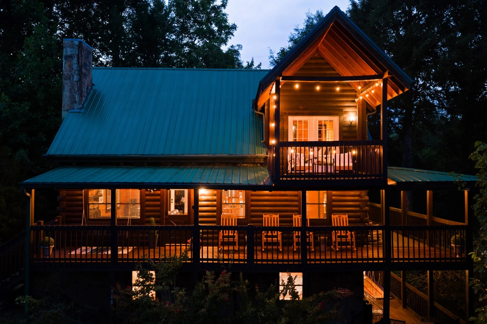 PeaksNPines at dusk, its green roof and timber balconies lit warmly against the trees